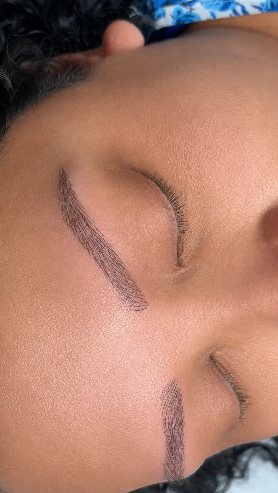 Cejas construidas trazo a trazo sobre una piel casi sin vello propio, con la clienta recostada y los ojos cerrados.