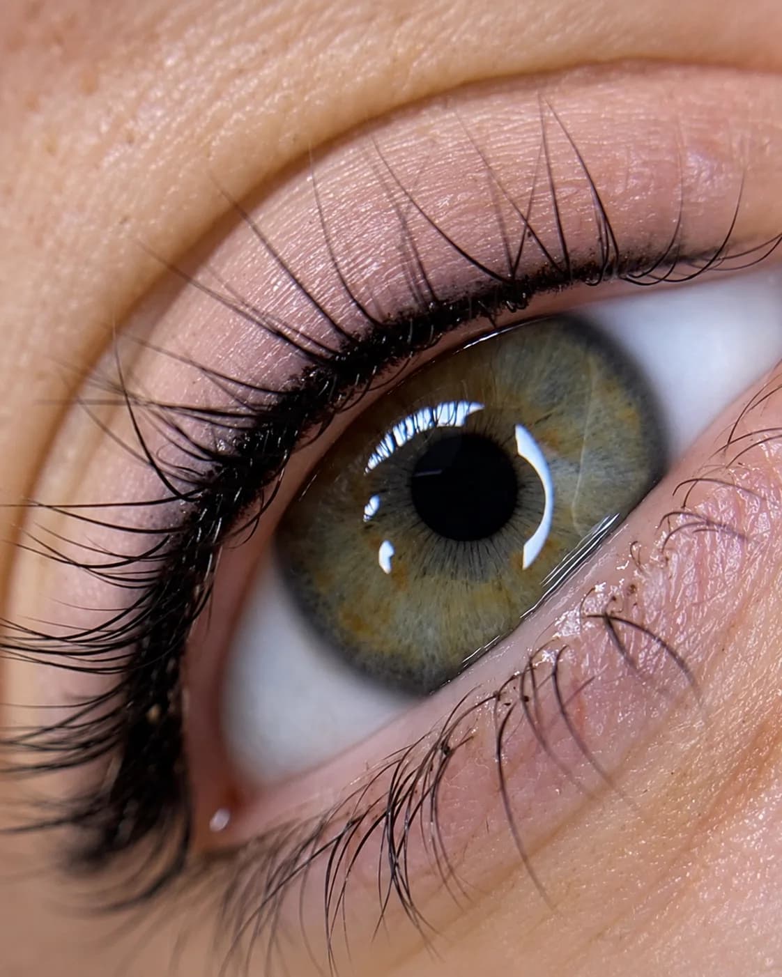 Primer plano de un ojo verde con densificado oscuro en la raíz de las pestañas, que espesa la mirada sin dibujar una línea sobre el párpado.