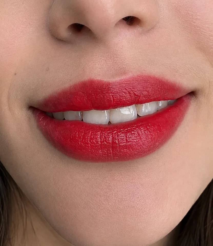 Sonrisa con los labios de color rojo parejo de comisura a comisura y el arco de cupido dibujado.