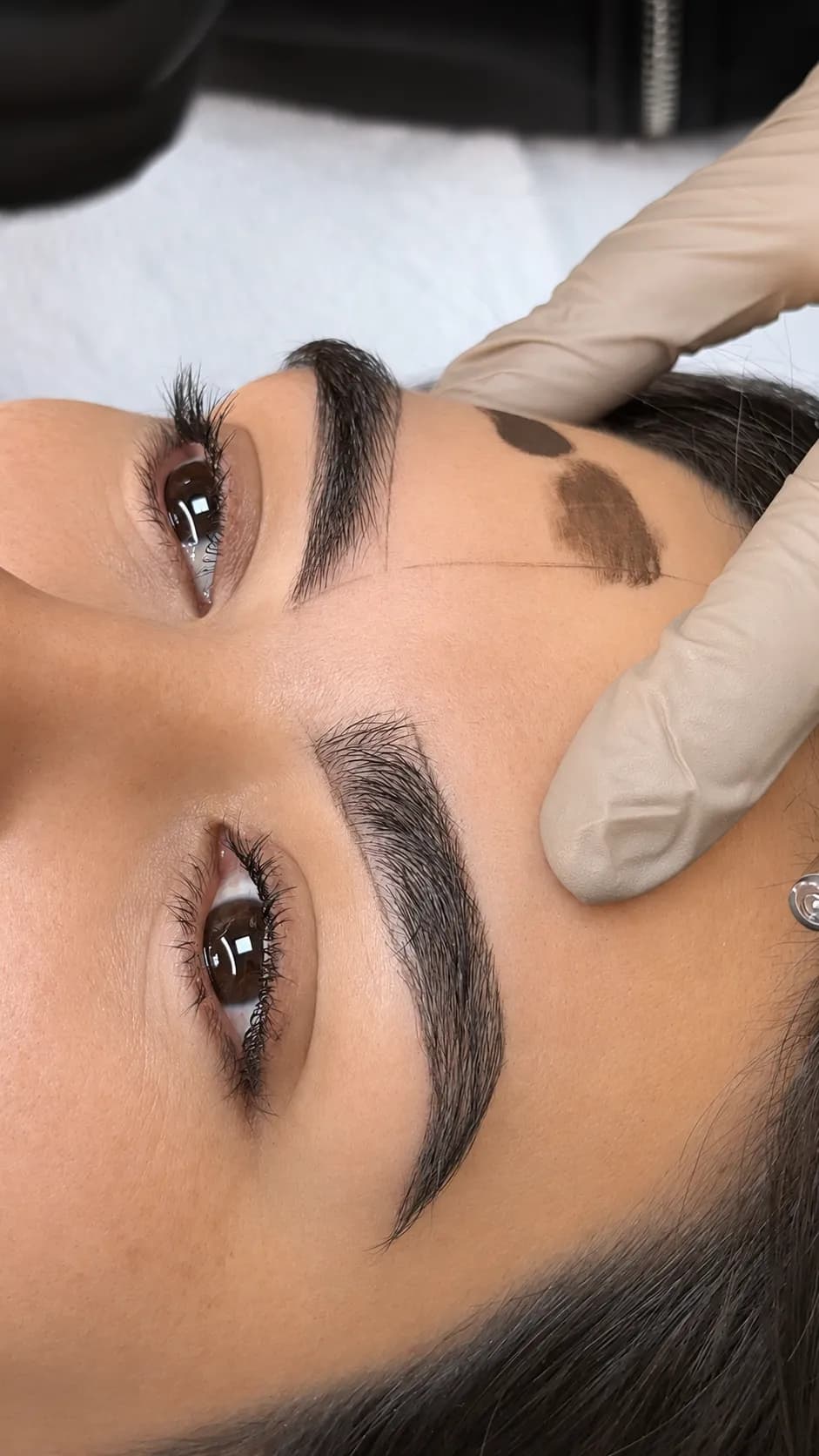 Cejas con vello natural denso, con puntos de prueba de pigmento marcados en la sien.